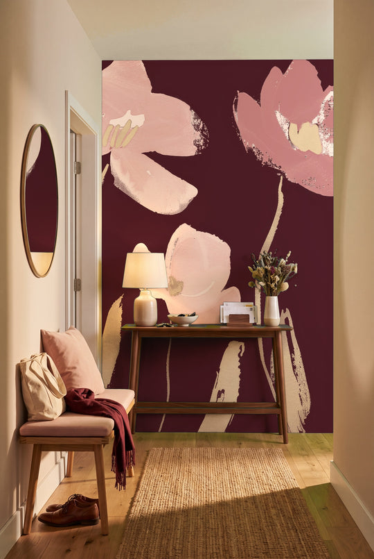 Entrée avec console en noyer et banc devant un papier peint panoramique floral bordeaux aux grandes fleurs rose poudré