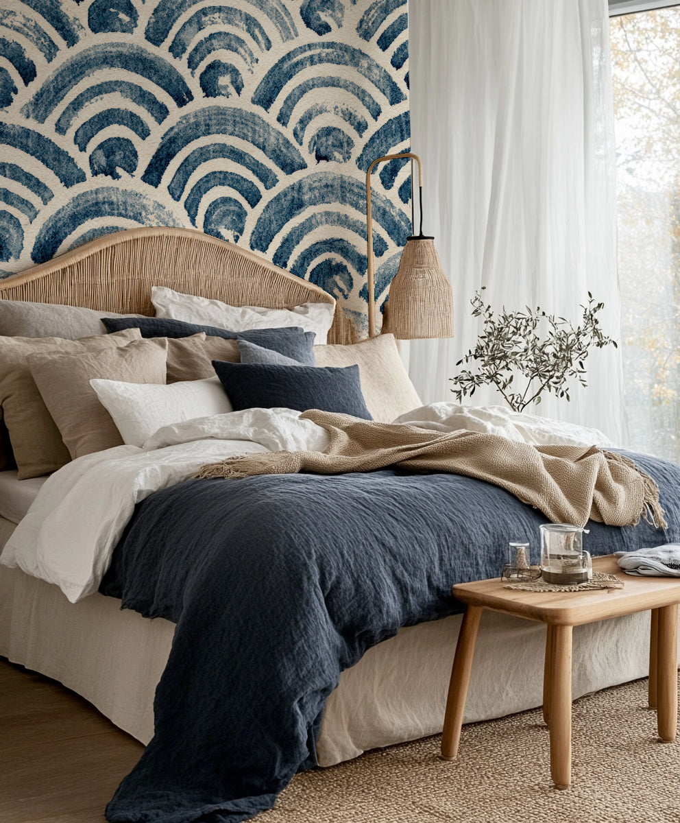 Chambre bohème à la tête de lit en rotin devant un papier peint seigaiha indigo
