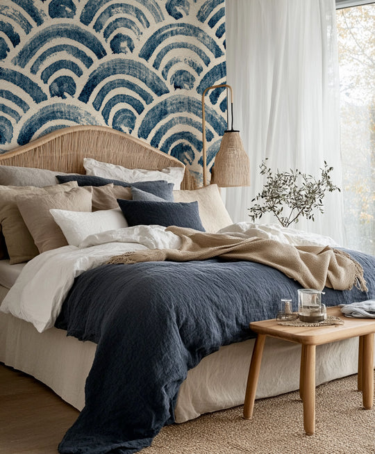 Chambre bohème à la tête de lit en rotin devant un papier peint seigaiha indigo