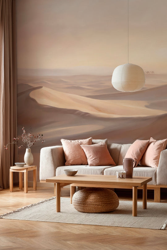 Salon avec canapé crème et coussins roses devant un papier peint panoramique désert beige rosé