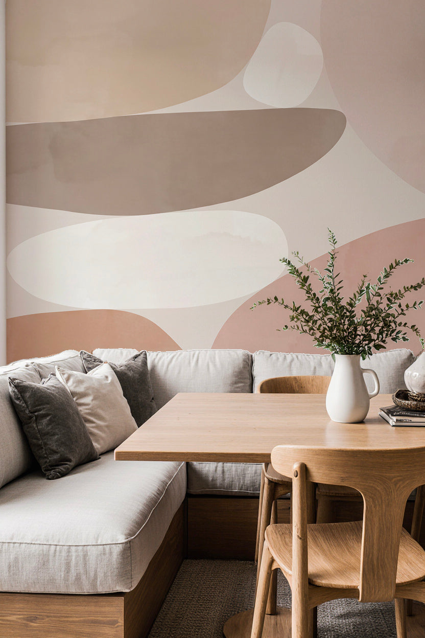Coin repas avec banquette et table en bois devant un papier peint panoramique abstrait beige, taupe et rose