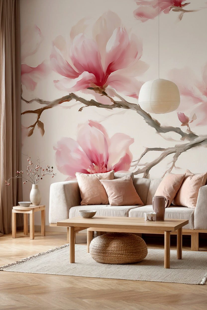 Salon avec canapé crème et coussins rose poudré devant un papier peint panoramique de branches de magnolias roses sur fond crème